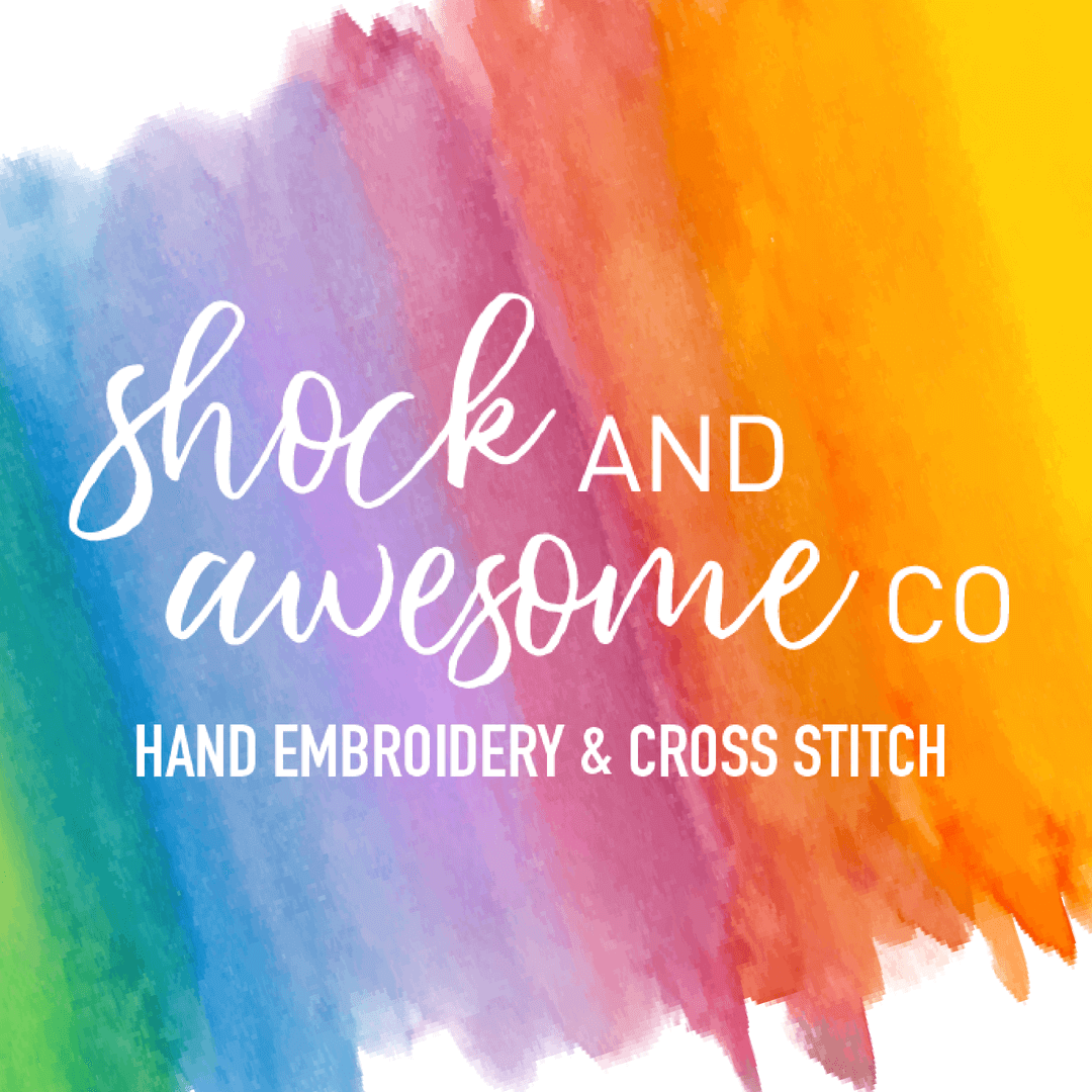 A rainbow watercolor background with the company name "Shock and Awesome Co" in a handwritten-style font about the words "Hand Embroidery & Cross Stitch" in a bold sans serif font.